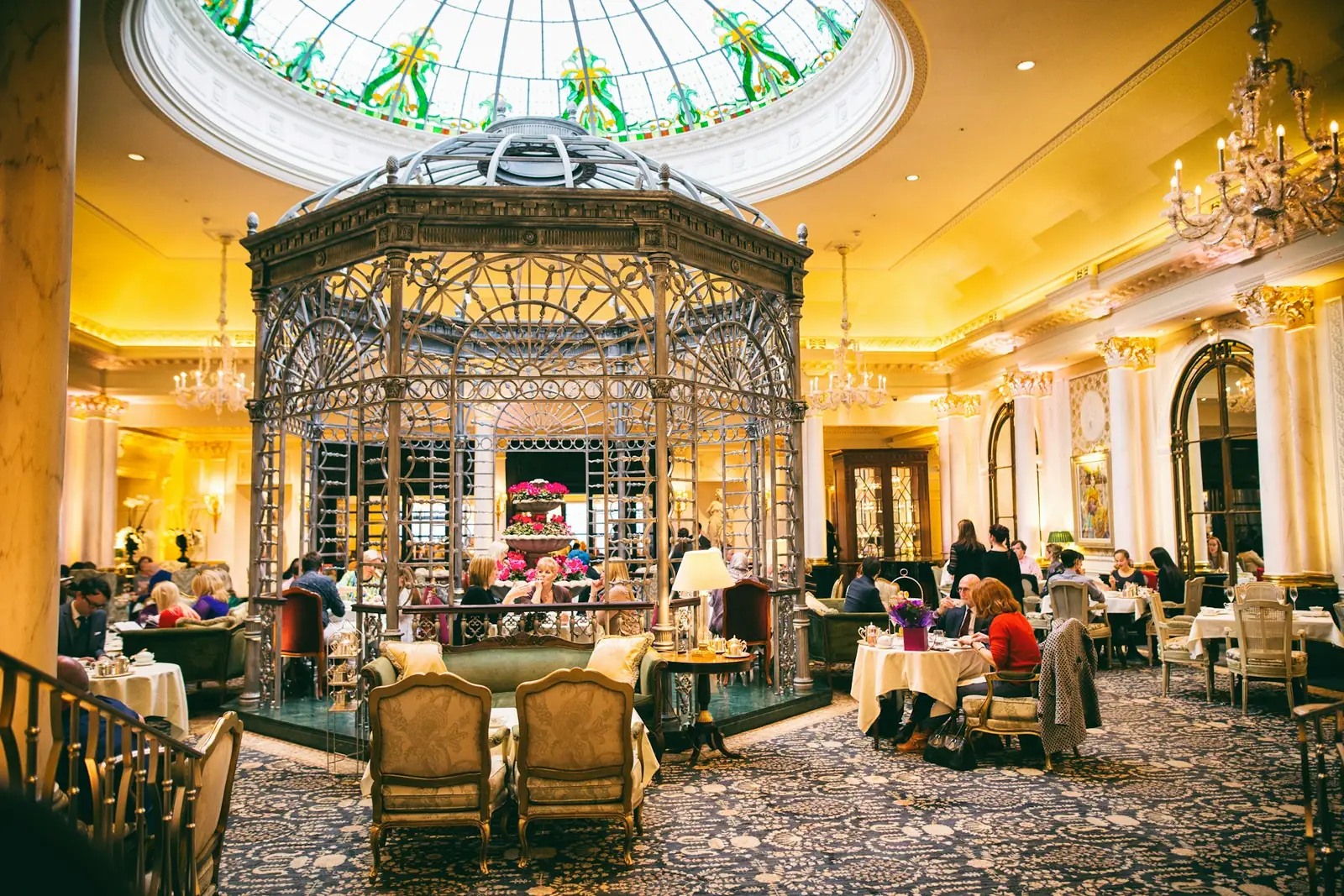 Guests at afternoon tea beneath the glass dome and central gazebo in the Savoy’s former Thames Foyer.