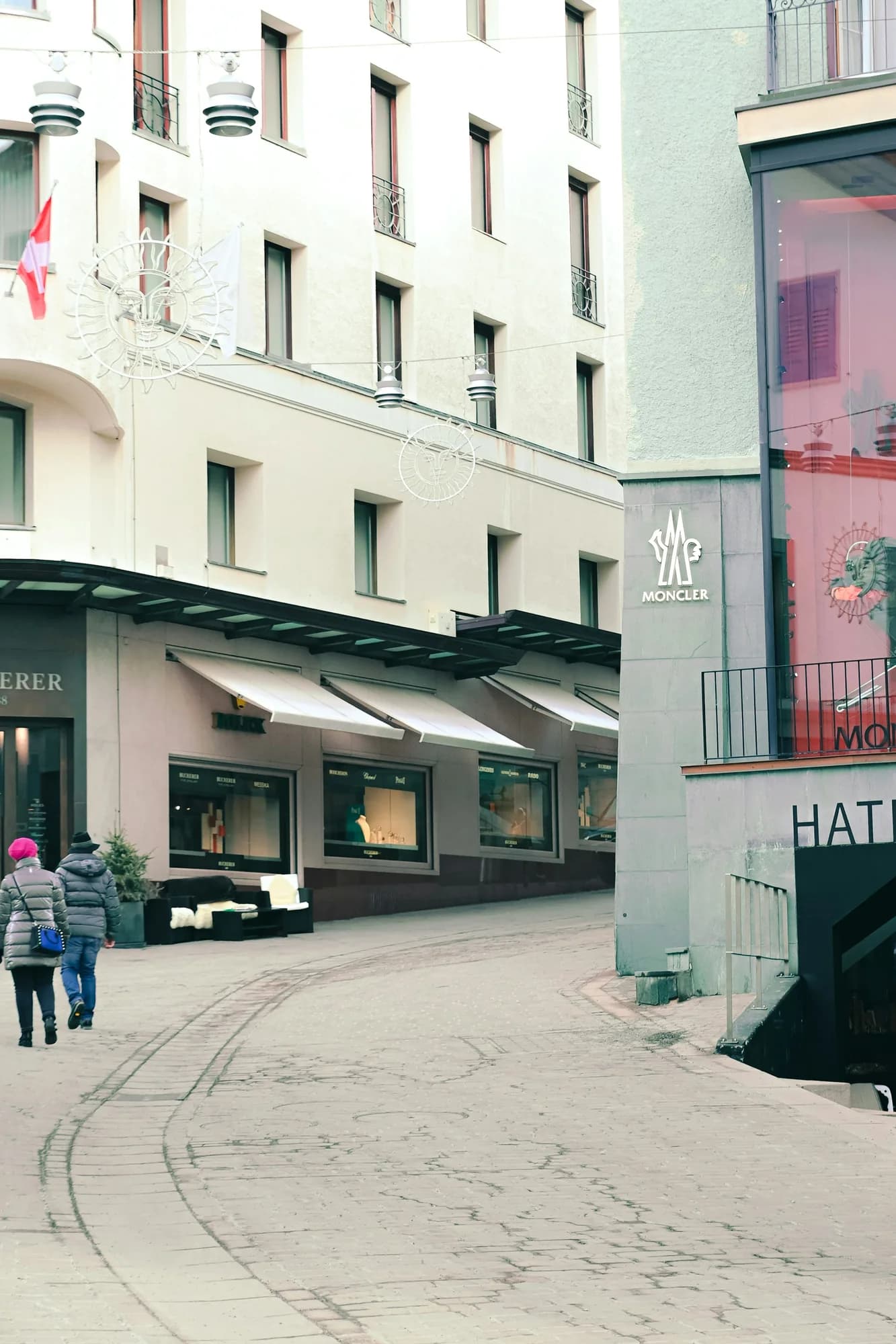 A curving street between pale building façades in St. Moritz.